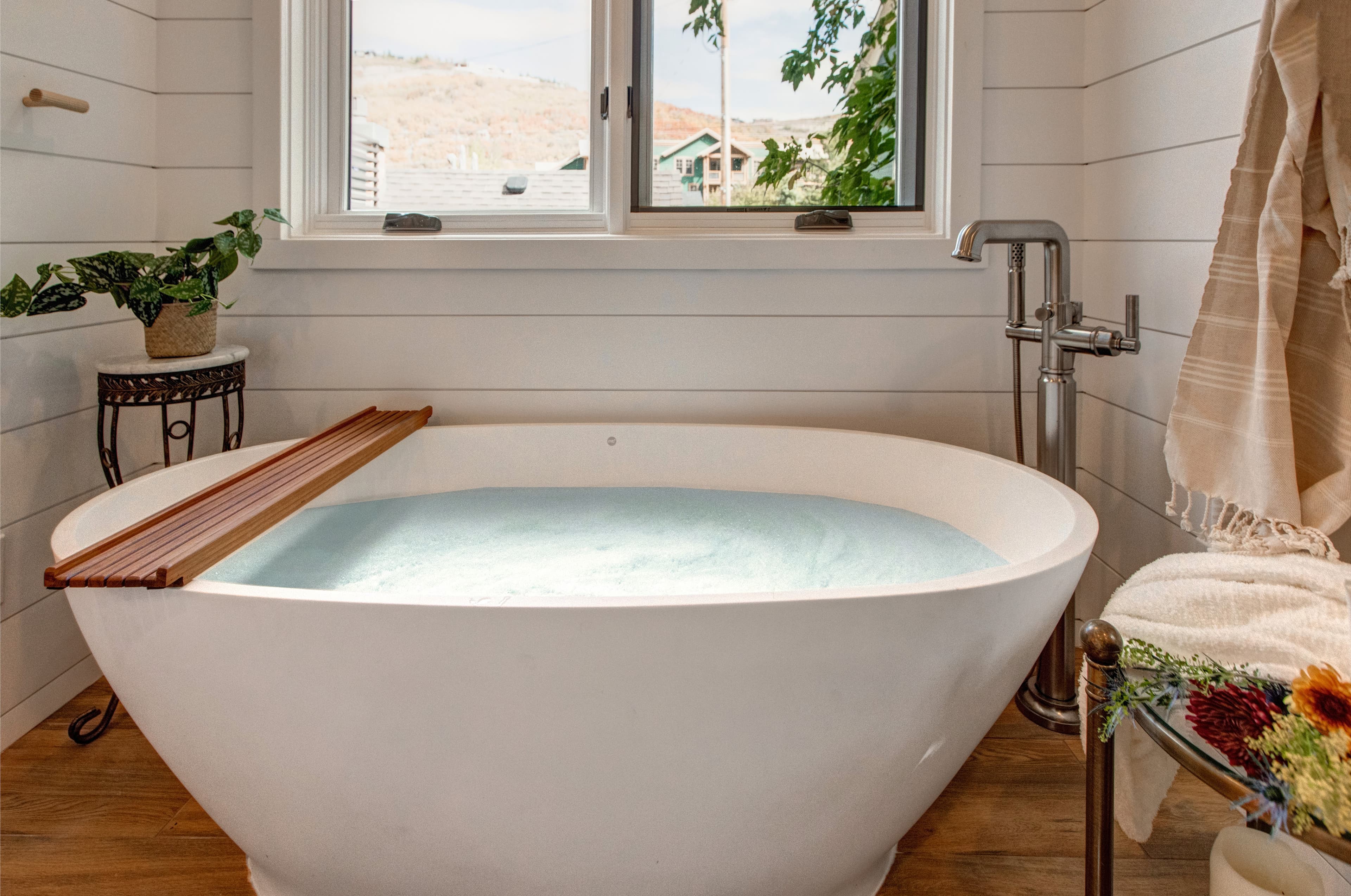 Lofted bedroom in detached guest suite, with a queen bed next to standalone bathtub.