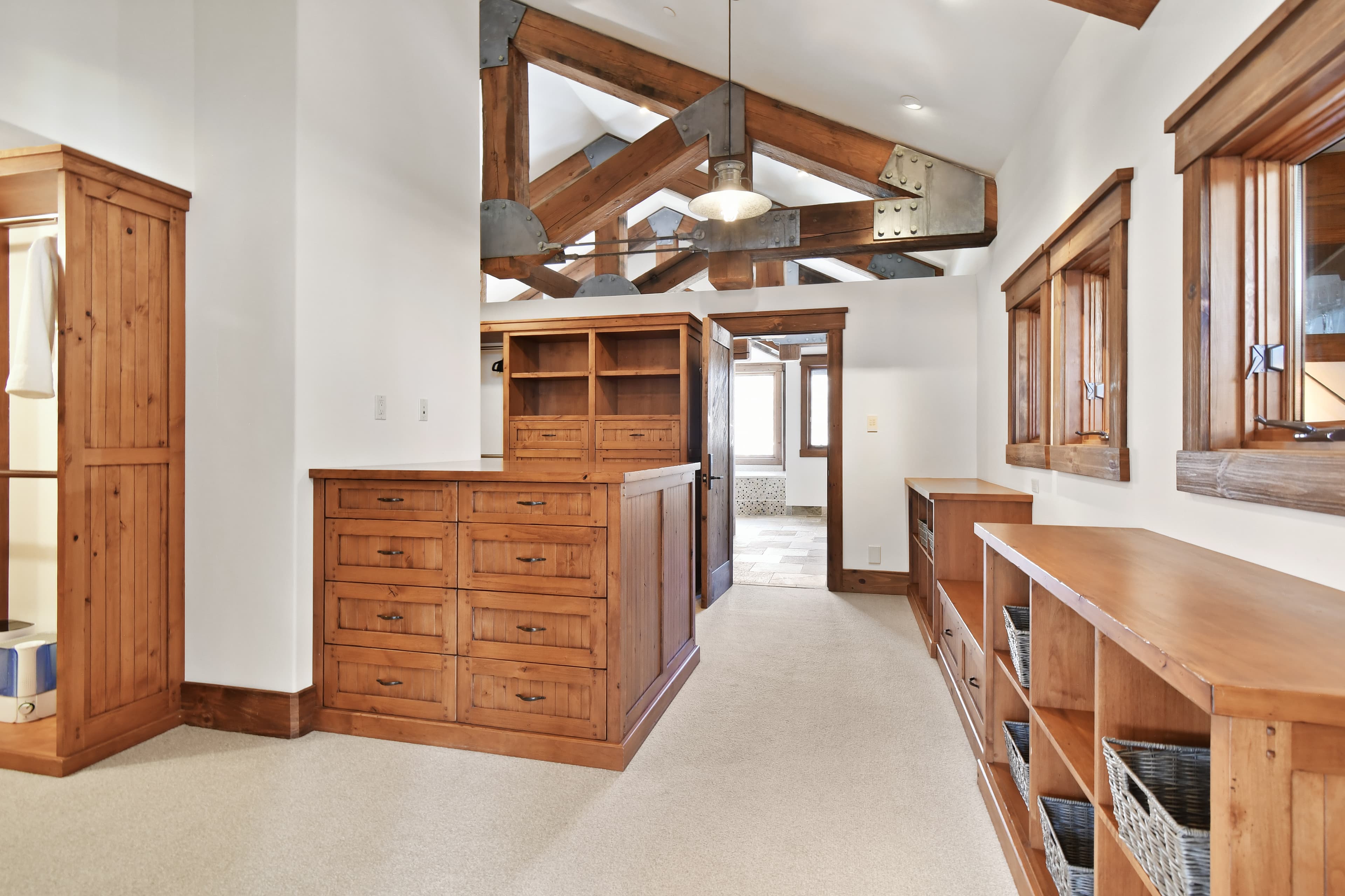 Wooden cabinets and shelves flank the walls of the primary bedroom's walk-in closet.