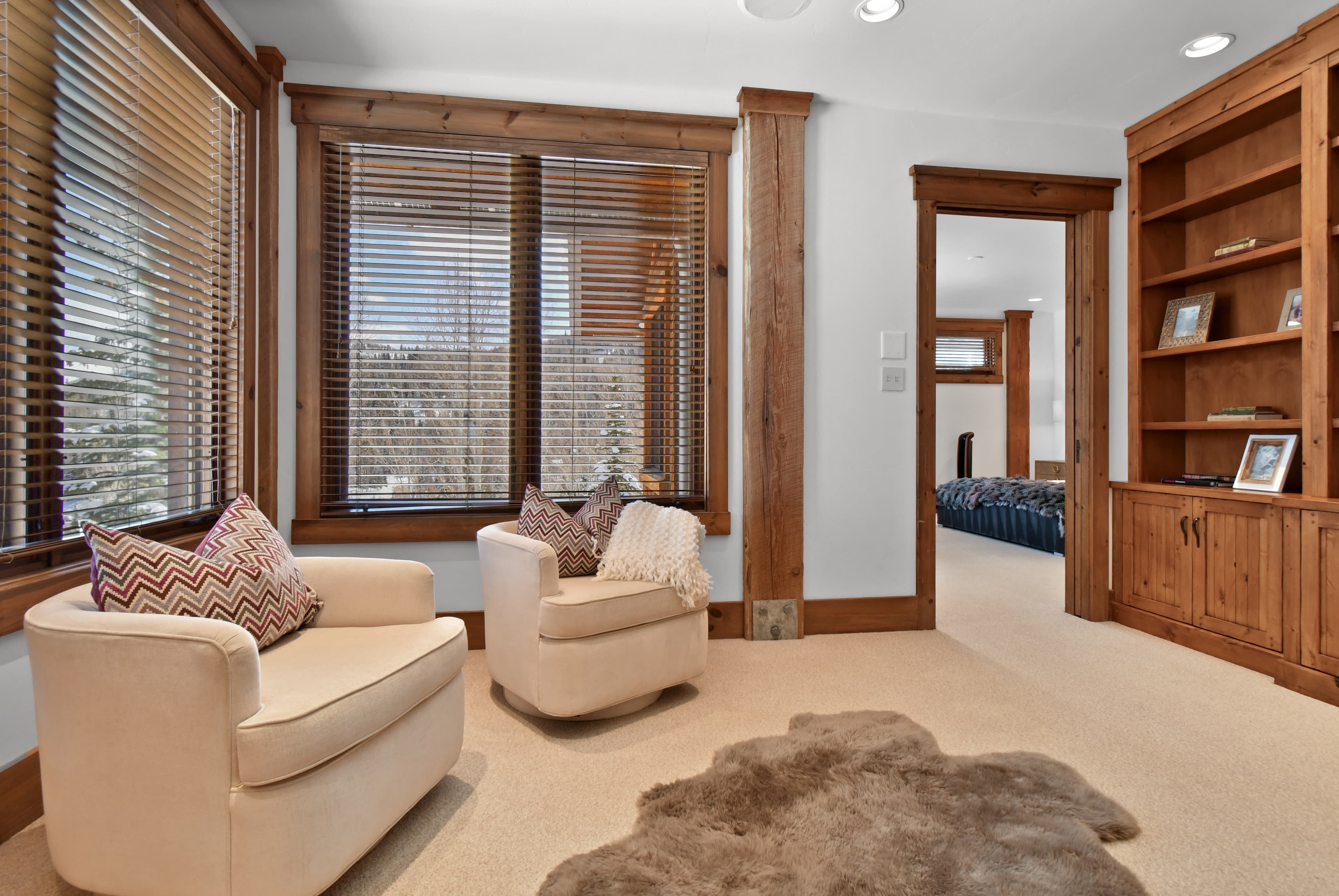 Two white armchairs flank the windowed walls of an office.