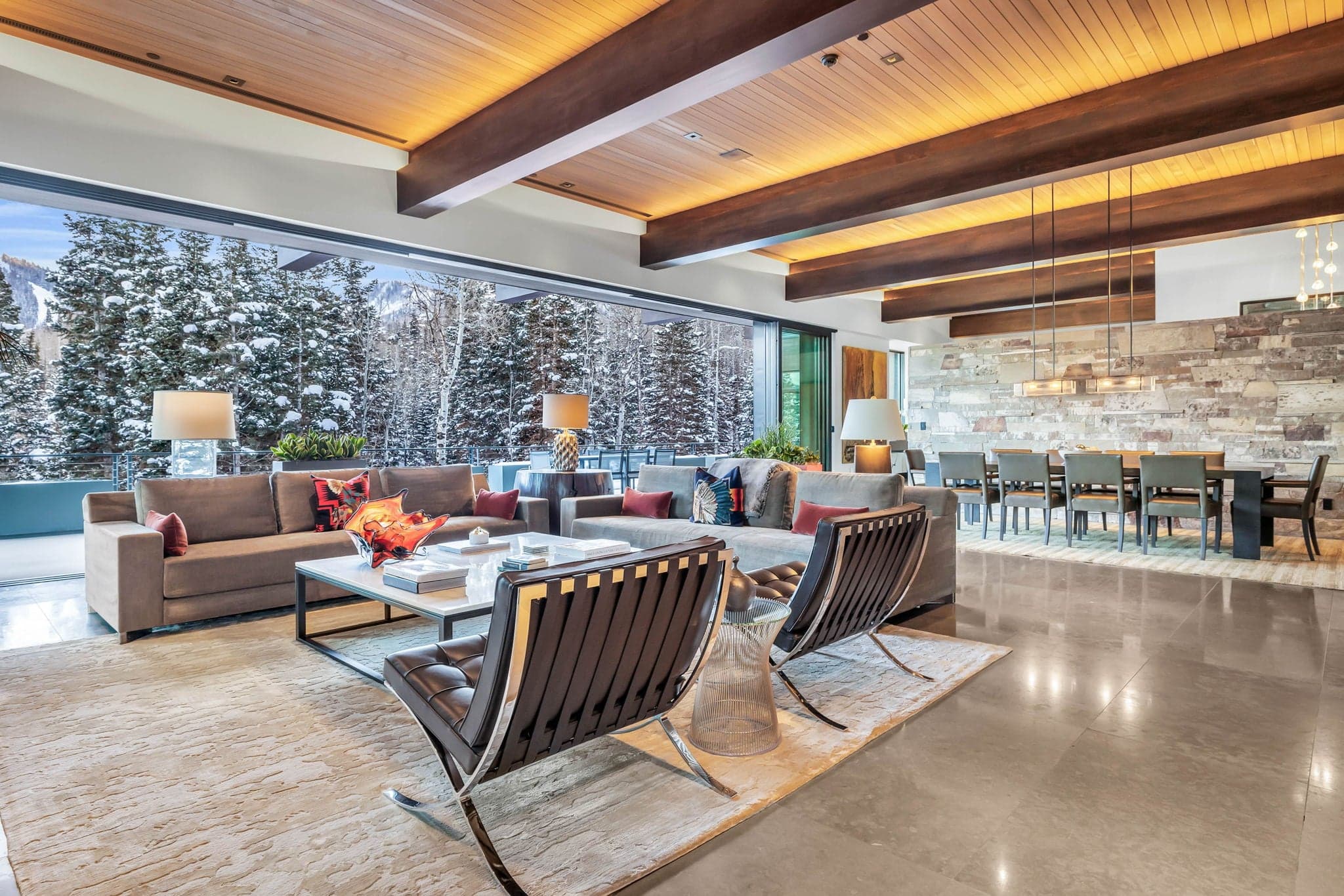 A sleek living space with floor-to-ceiling windows, modern decor, and stunning snowy views.