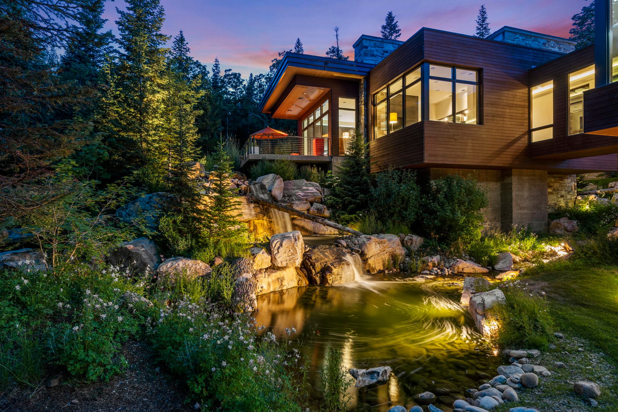 A White Pine Canyon Ranch luxury Park City vacation rental with a serene waterfall and lush greenery.