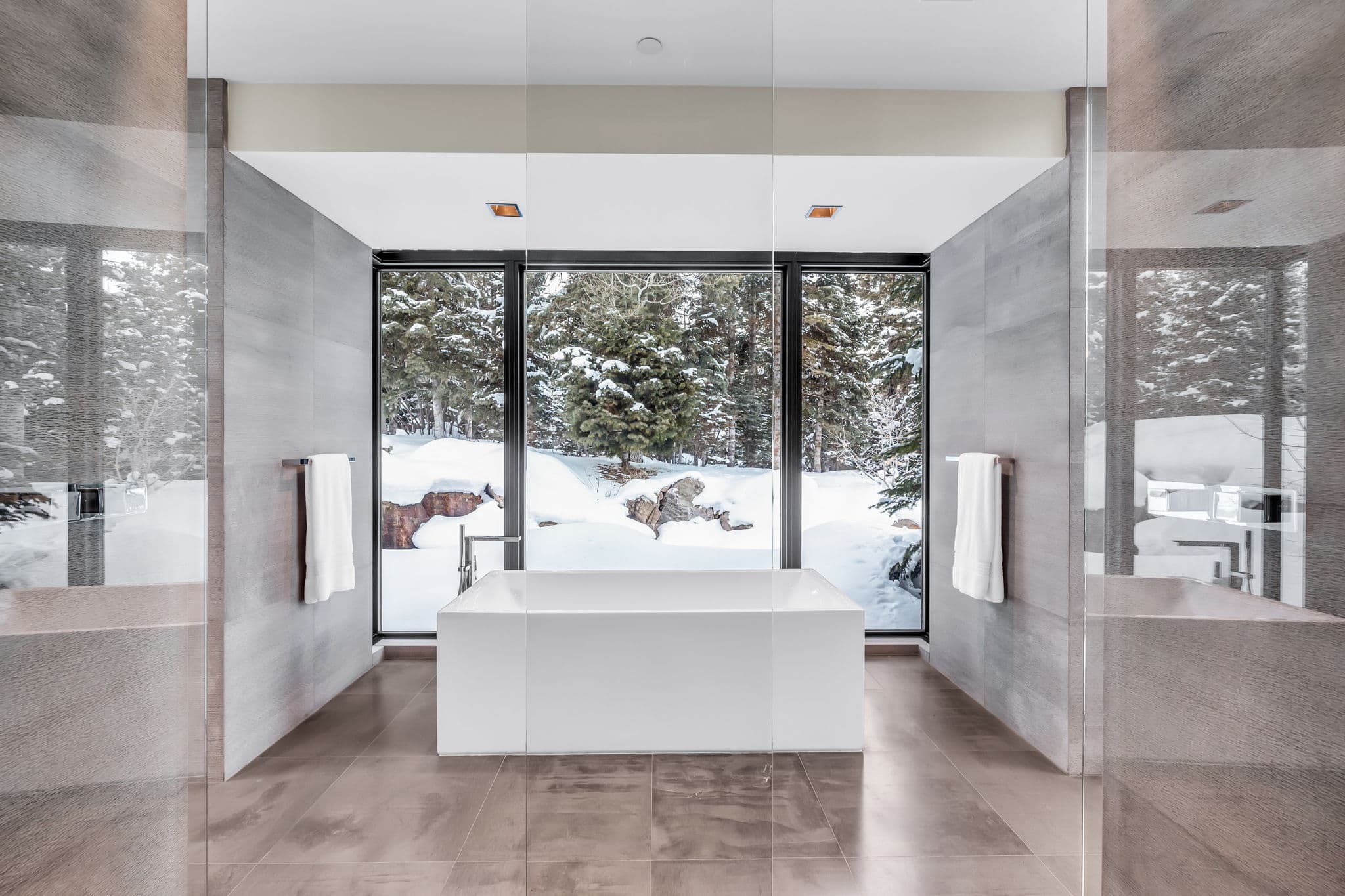 A spa-like bathroom with a soaking tub and snowy views.