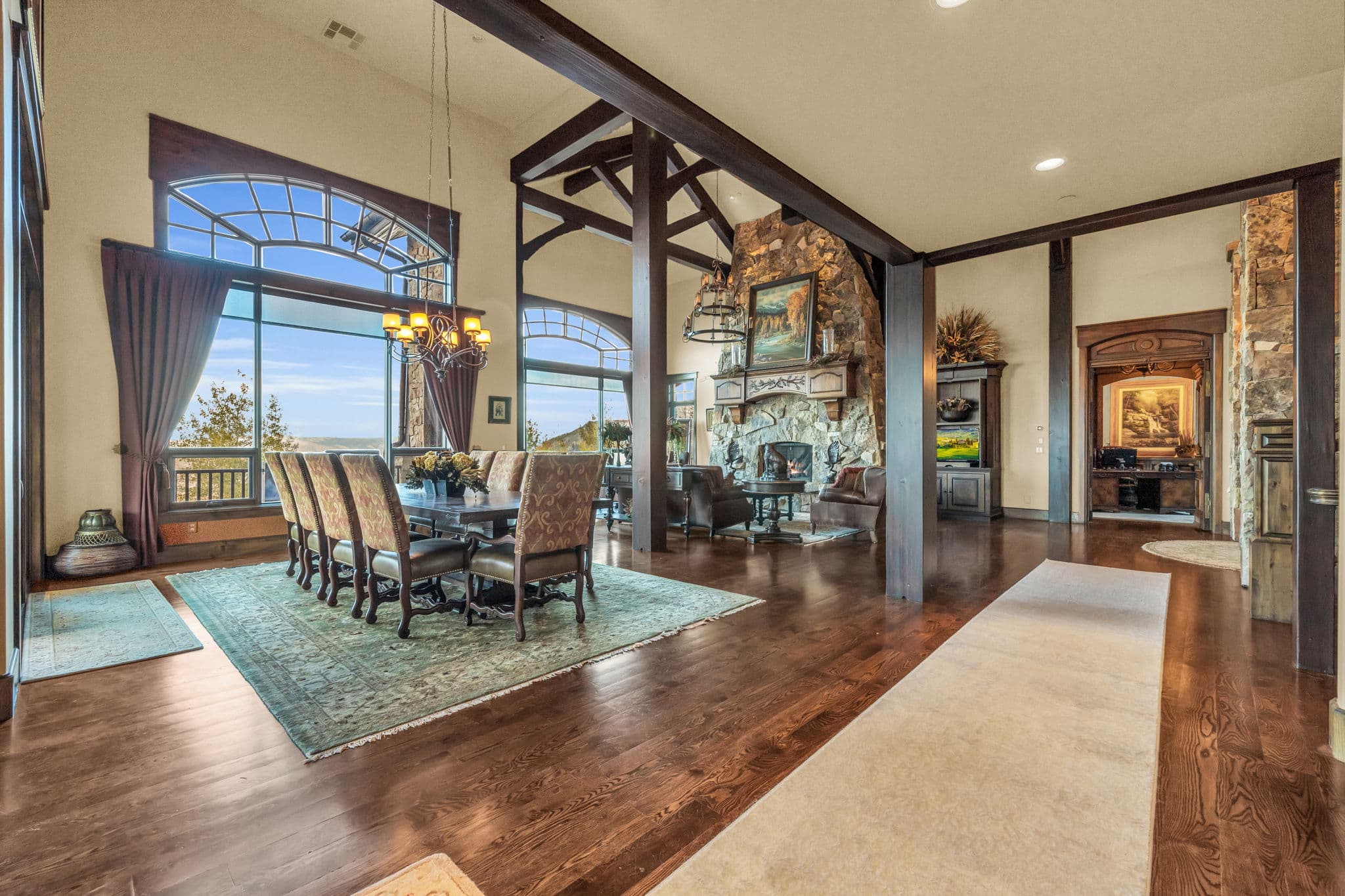 Spacious living room  with paintings, chandelier, dining room, and fireplace.
