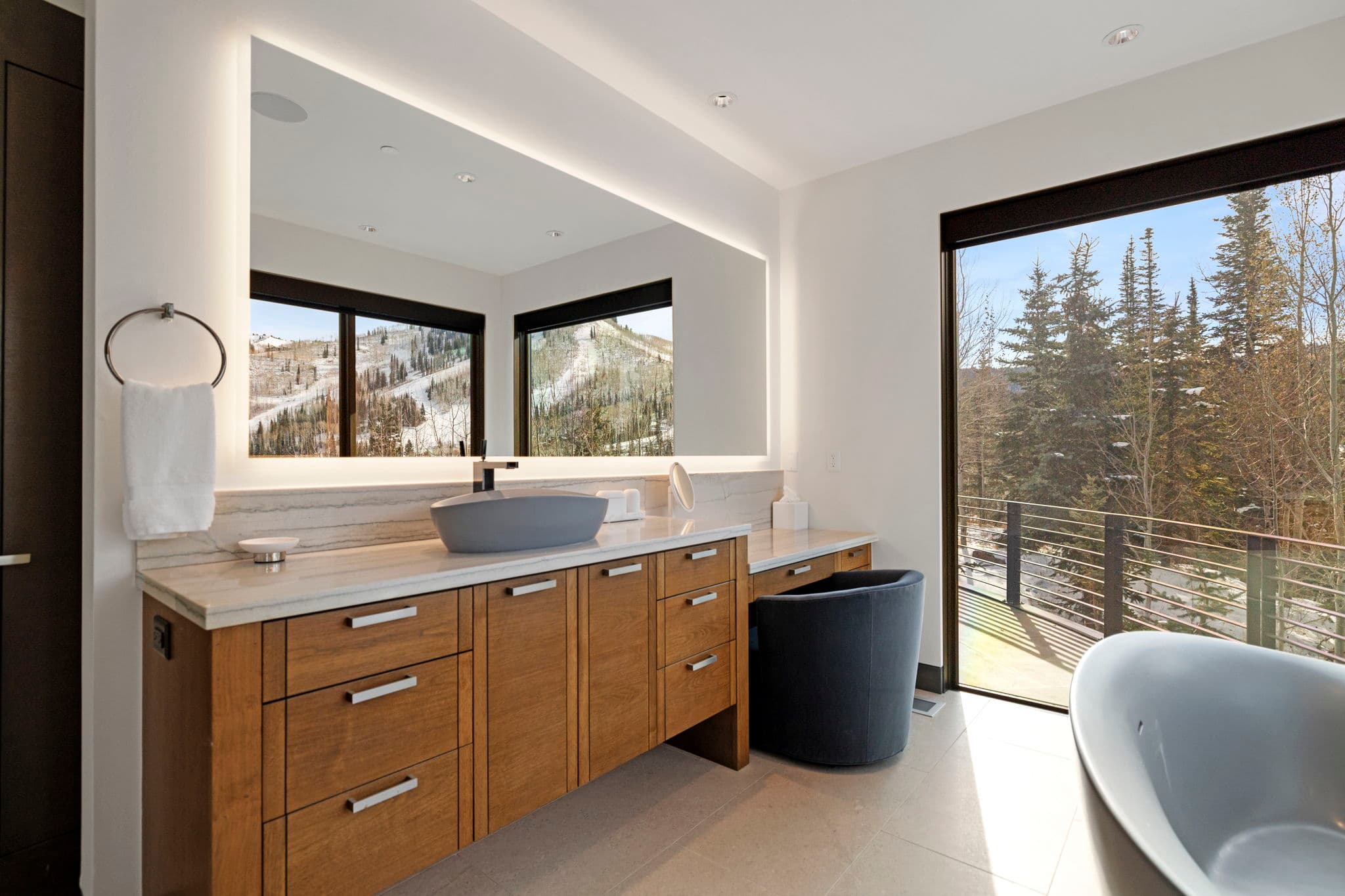 A view of a bathroom sink and a large mirror.