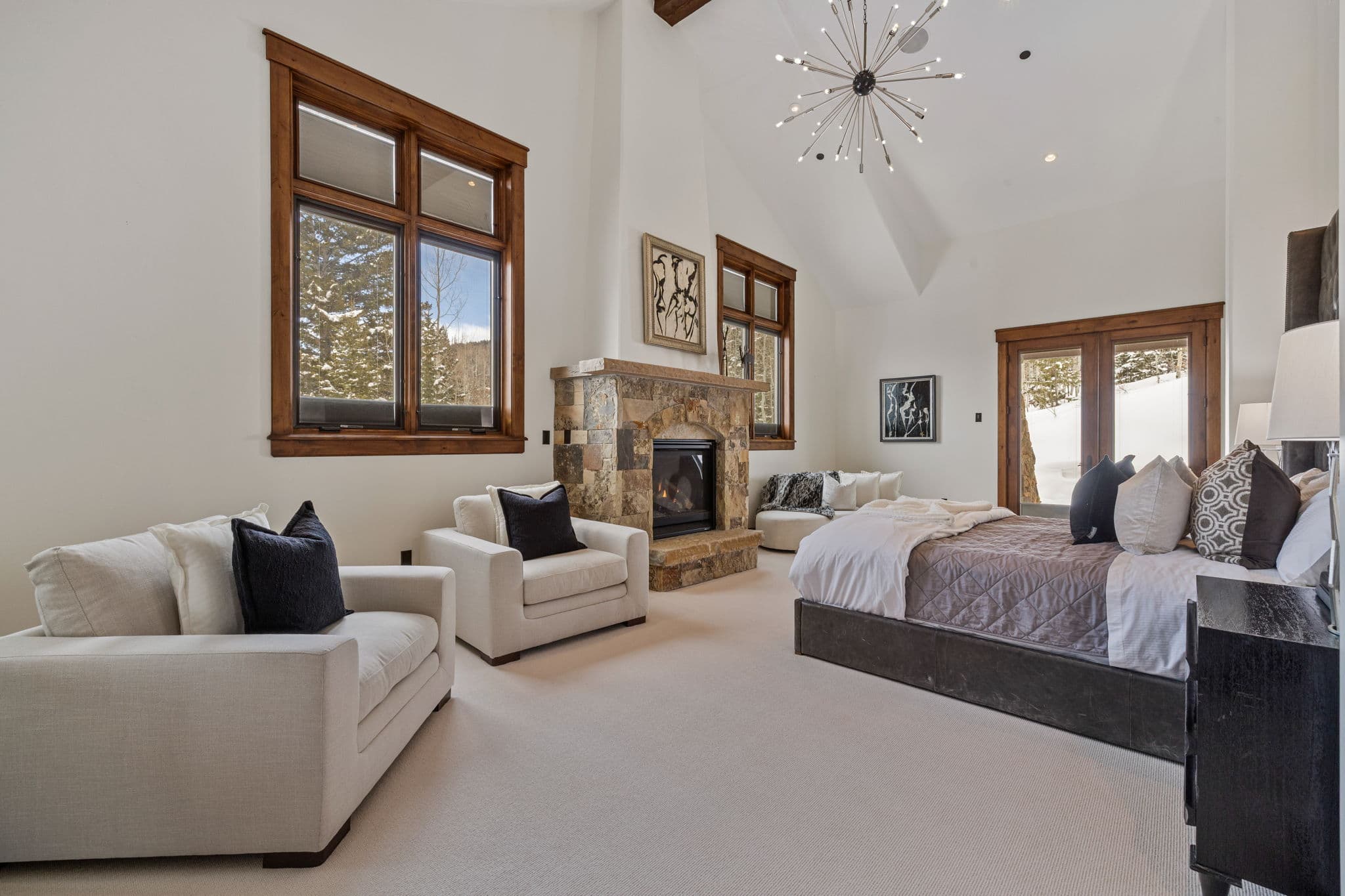 the primary master suite with king bed and lounge chairs and a stone fireplace