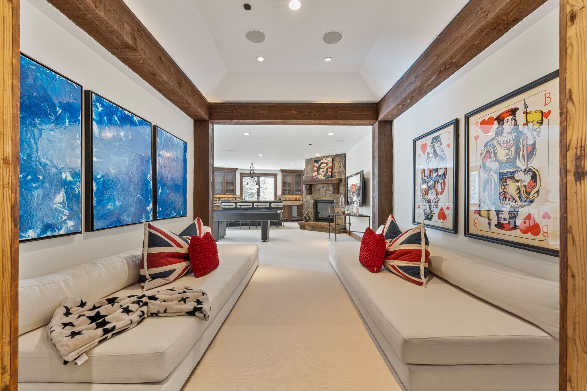 lower level game room with bright artwork and large white cozy couches