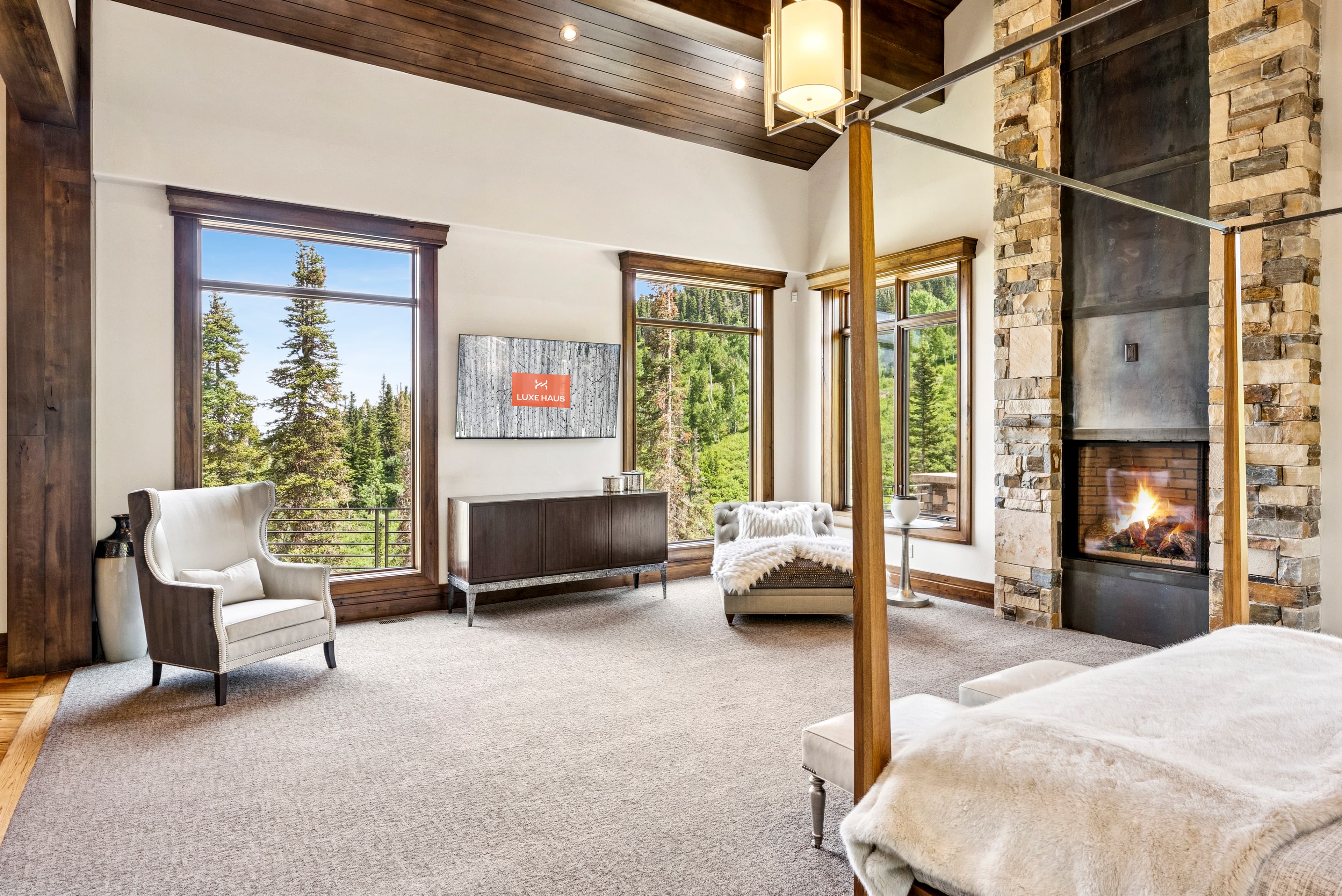 large primary suite with flatscreen tv that says "luxe haus" on the screen