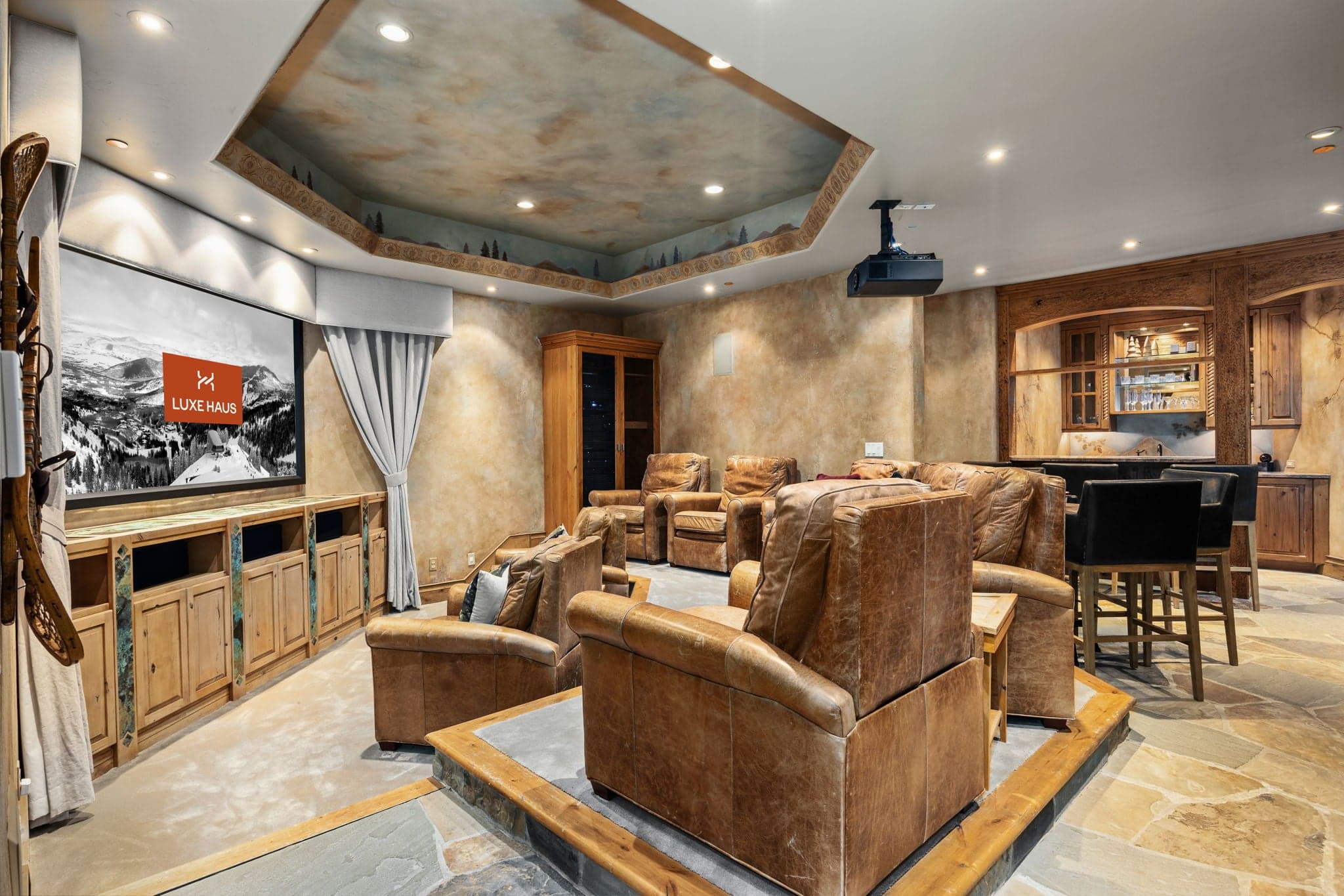 home theater area with giant TV and stuffed recliners with a bar area